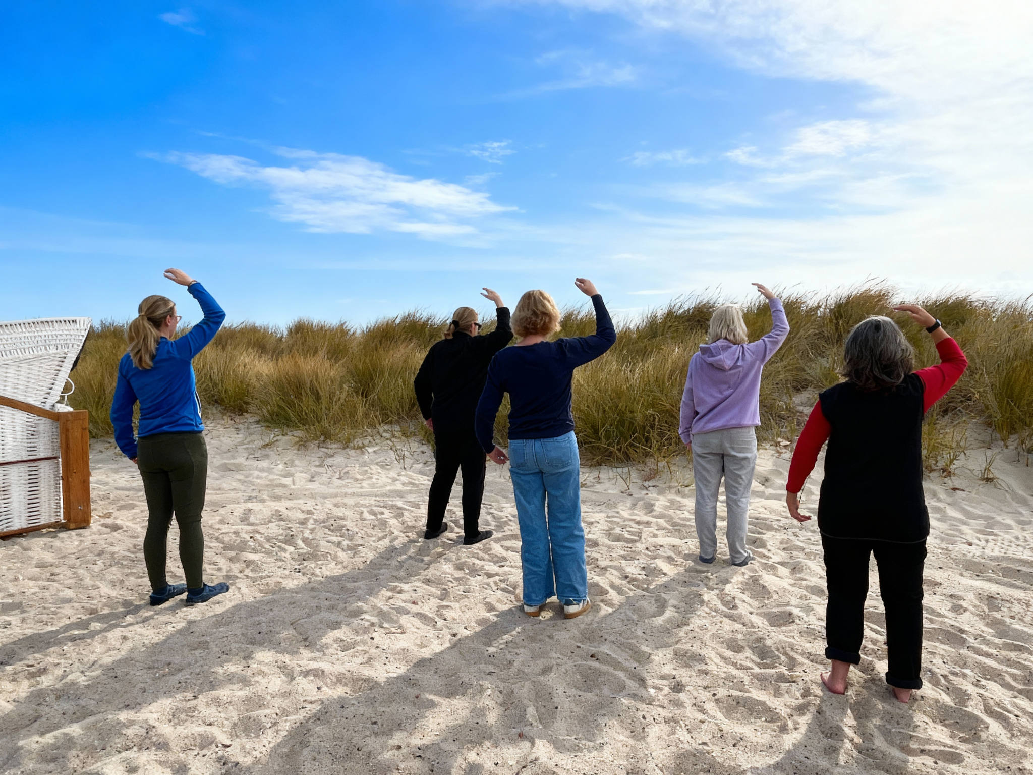5 Frauen machen Qigong am Ostseestrand bei einer Auszeit am Meer 