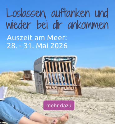 Eine Frau sitzt in den Dünen und genießt die Auszeit am Meer.